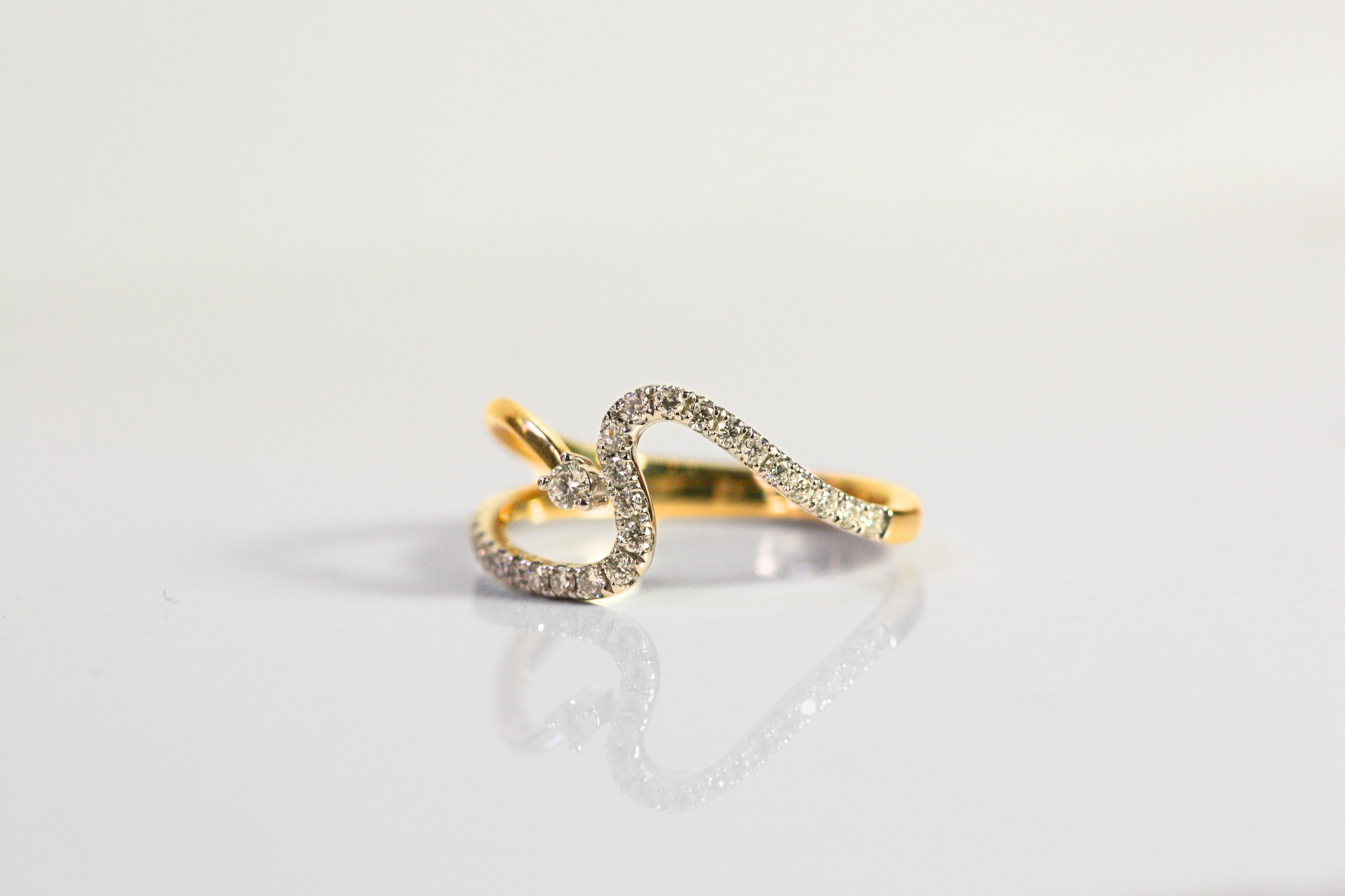 Wave ring. Diamonds all along the wave with a single round diamond floating next to the crest of the wave. Diamonds are set in white gold, while the rest of the ring is yellow gold. Local SF jewelry, San francisco, Luxury, hand made, Bay area, gift for her.