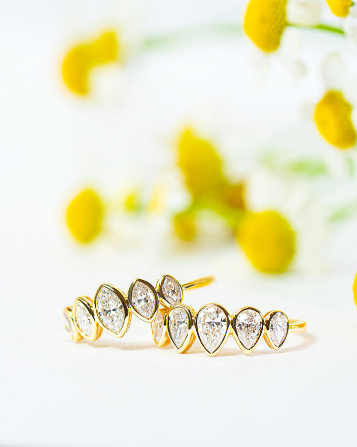 Two gold rings with diamonds on a white background with yellow flowers.