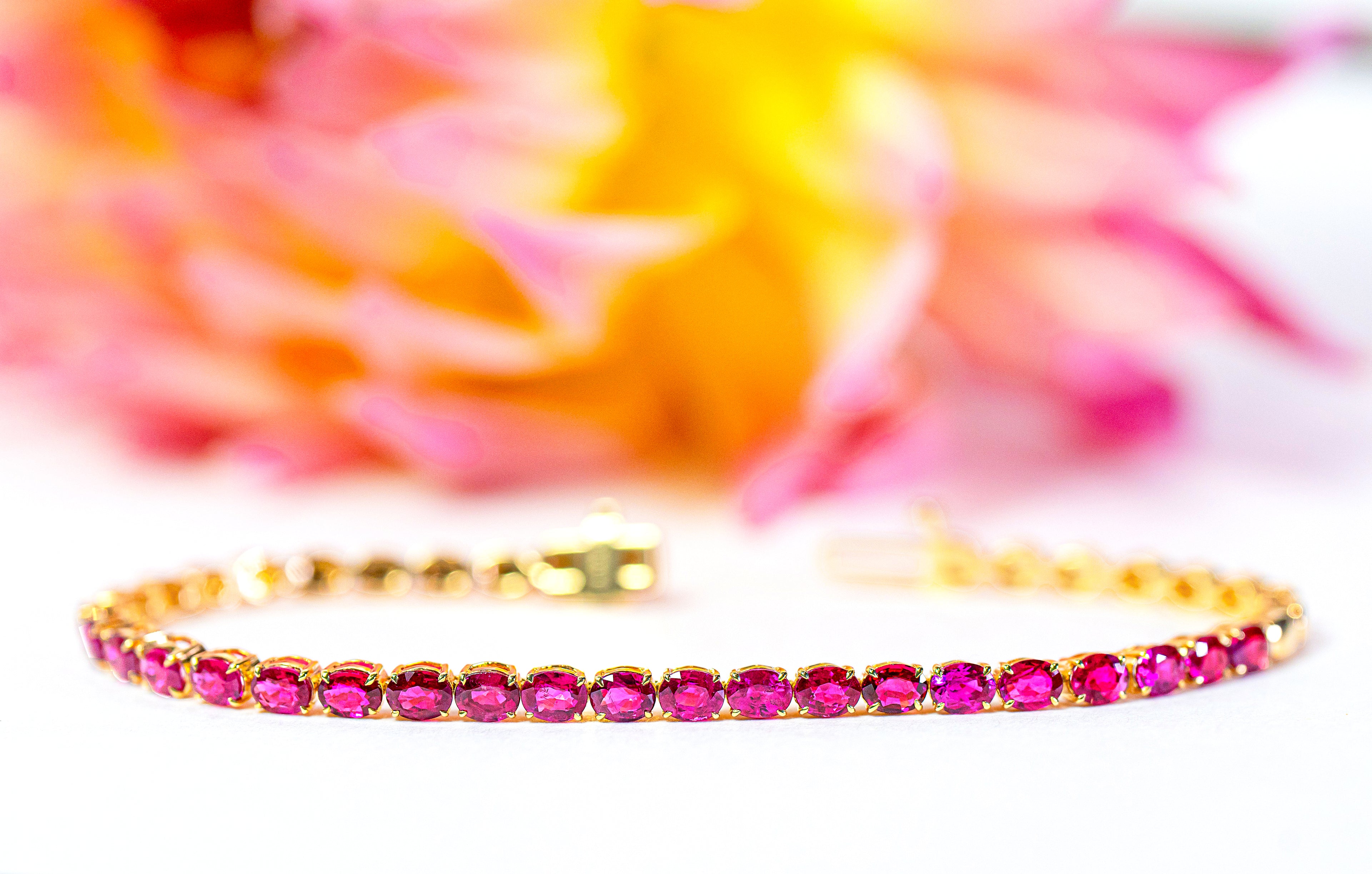 Gold bracelet with pink rubies on a colorful background