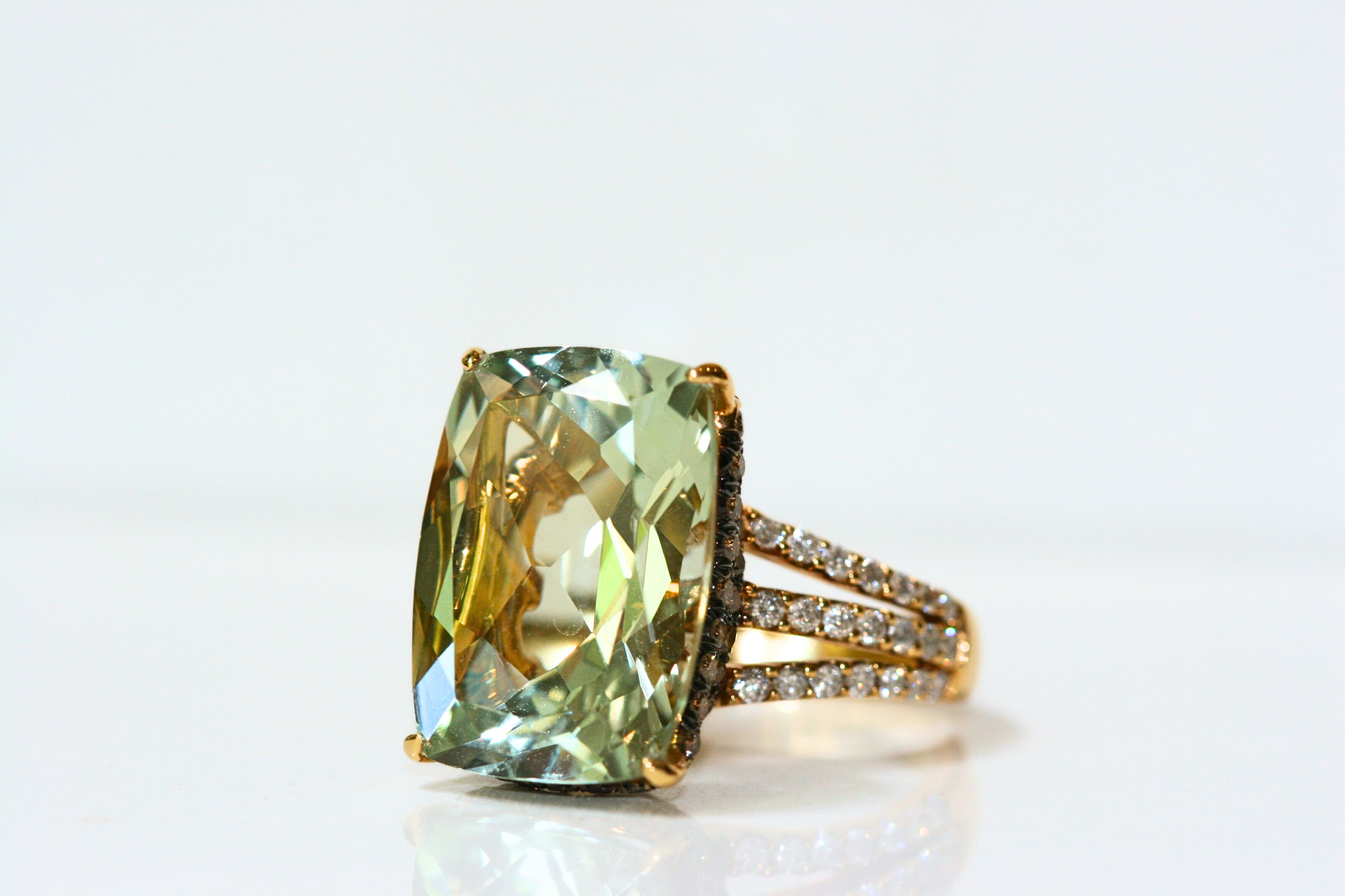 Elongated, cushion cut green quartz ring. Held in place by yellow gold claw prongs. There is subtle, hidden halo of brown diamonds set in black rhodium plated white gold. The shank of the ring is three strands of yellow gold, pave set with white diamonds.