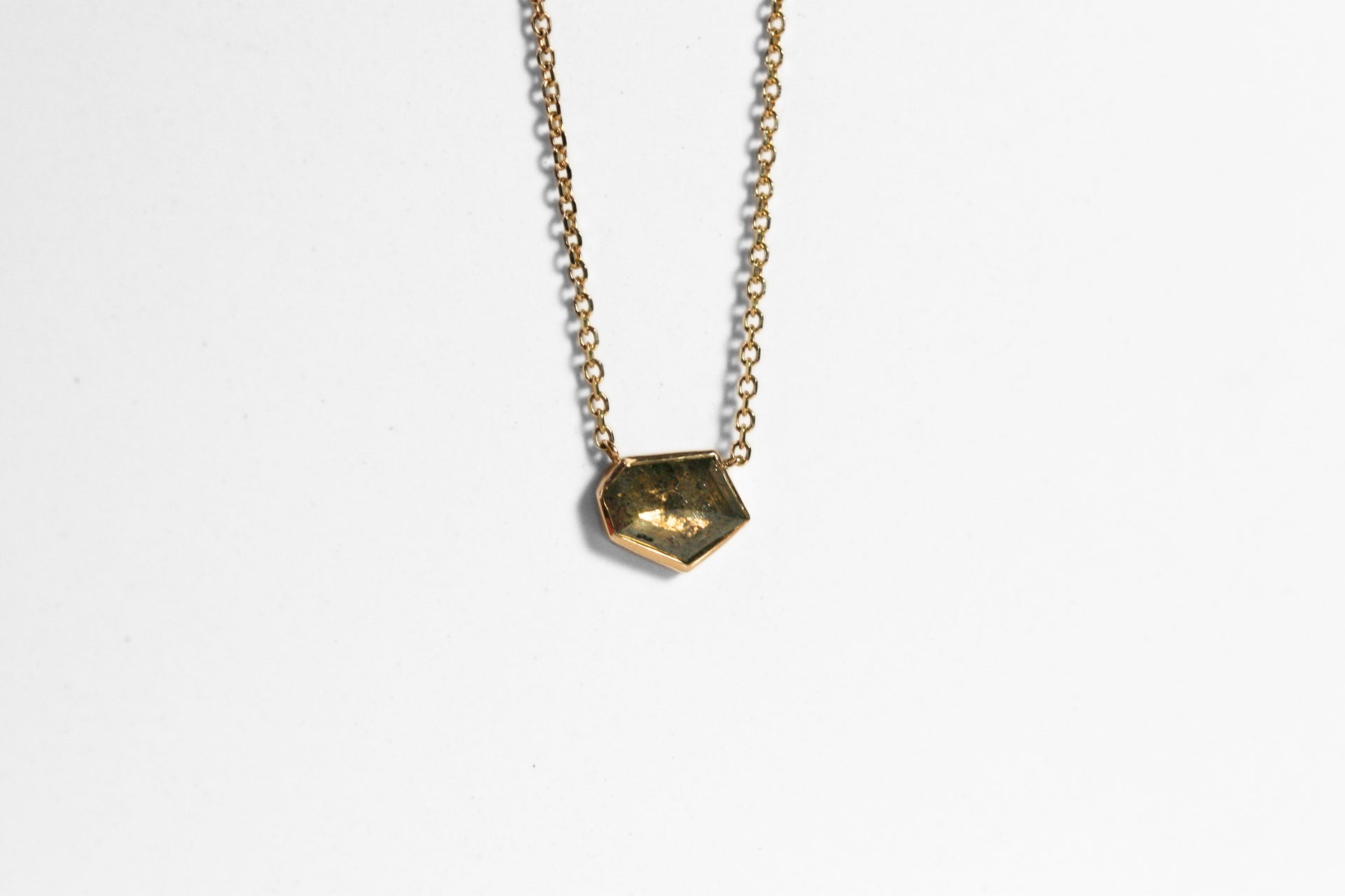 Abstract salt and pepper diamond is bezel set in yellow gold. Pendant, attached to a yellow gold rolo chain. Diamond has interesting inclusions.
