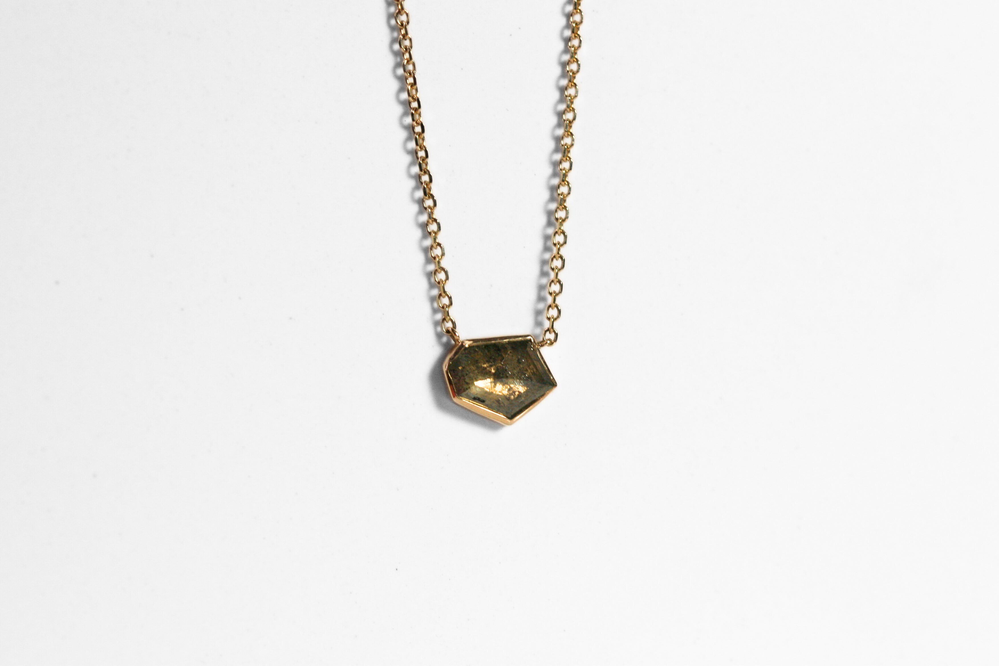 Abstract salt and pepper diamond is bezel set in yellow gold. Pendant, attached to a yellow gold rolo chain. Diamond has interesting inclusions.