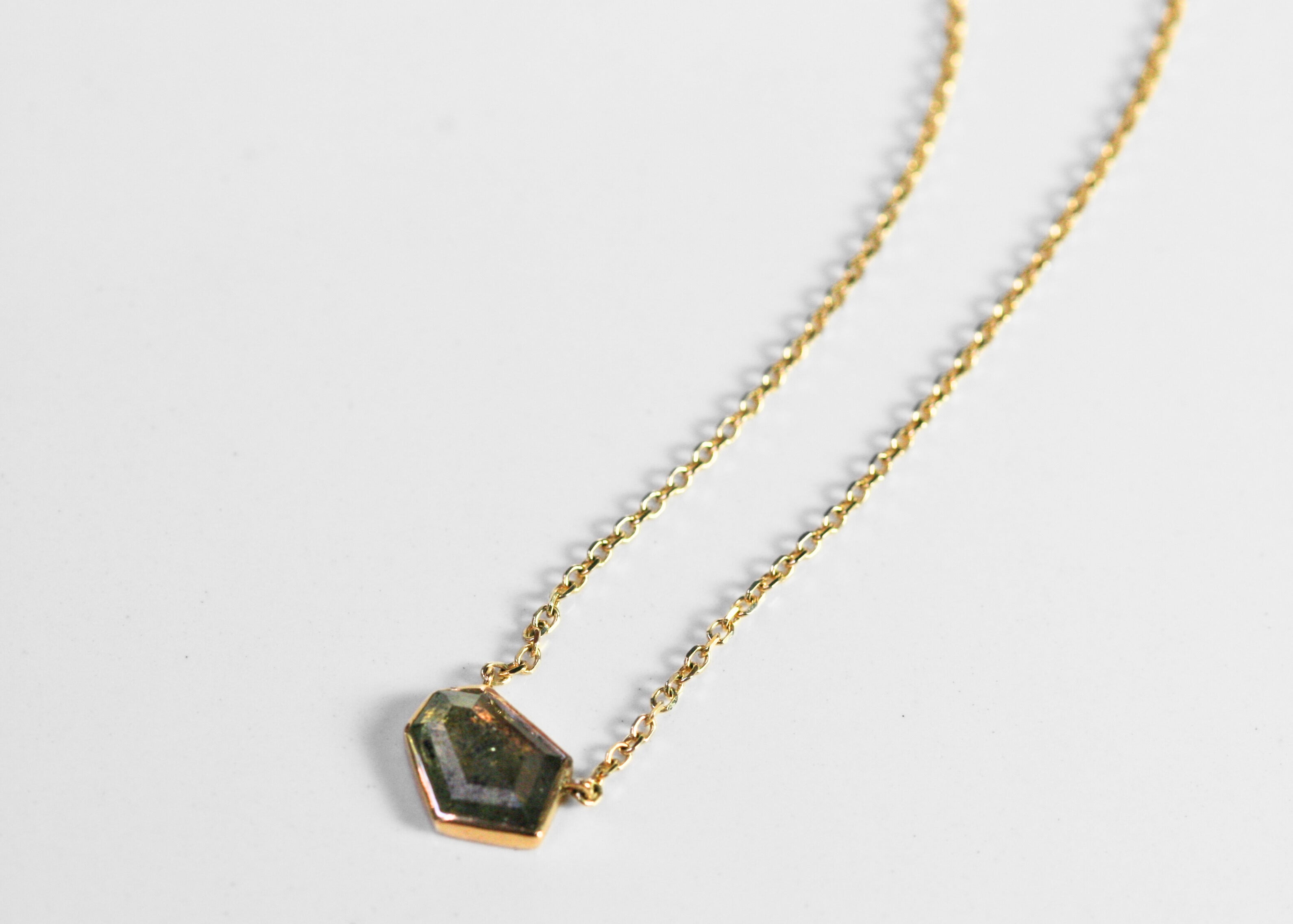 Abstract salt and pepper diamond is bezel set in yellow gold. Pendant, attached to a yellow gold rolo chain. Diamond has interesting inclusions.