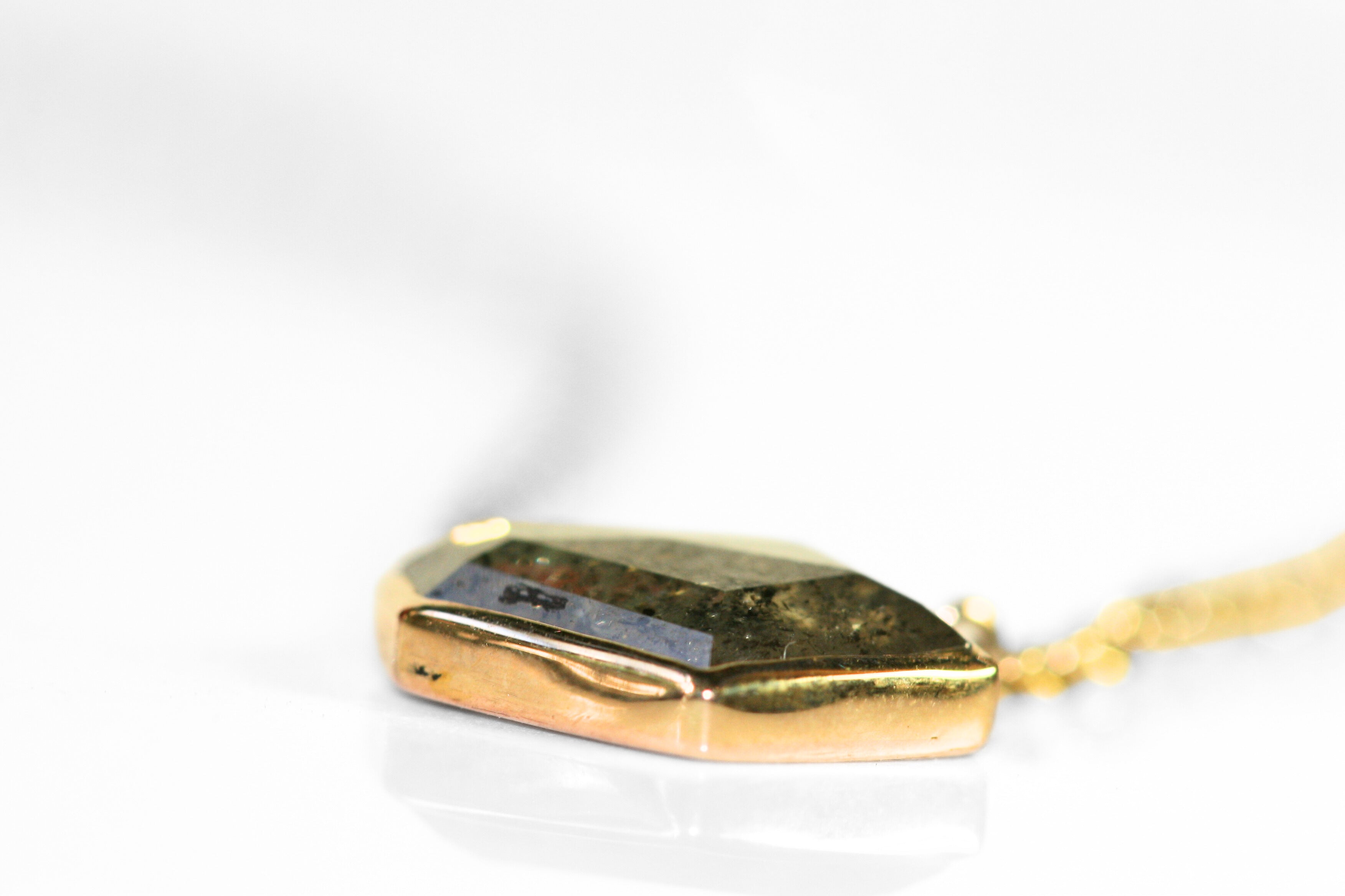 Abstract salt and pepper diamond is bezel set in yellow gold. Pendant, attached to a yellow gold rolo chain. Diamond has interesting inclusions.