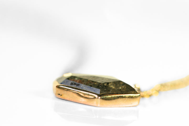 Abstract salt and pepper diamond is bezel set in yellow gold. Pendant, attached to a yellow gold rolo chain. Diamond has interesting inclusions.