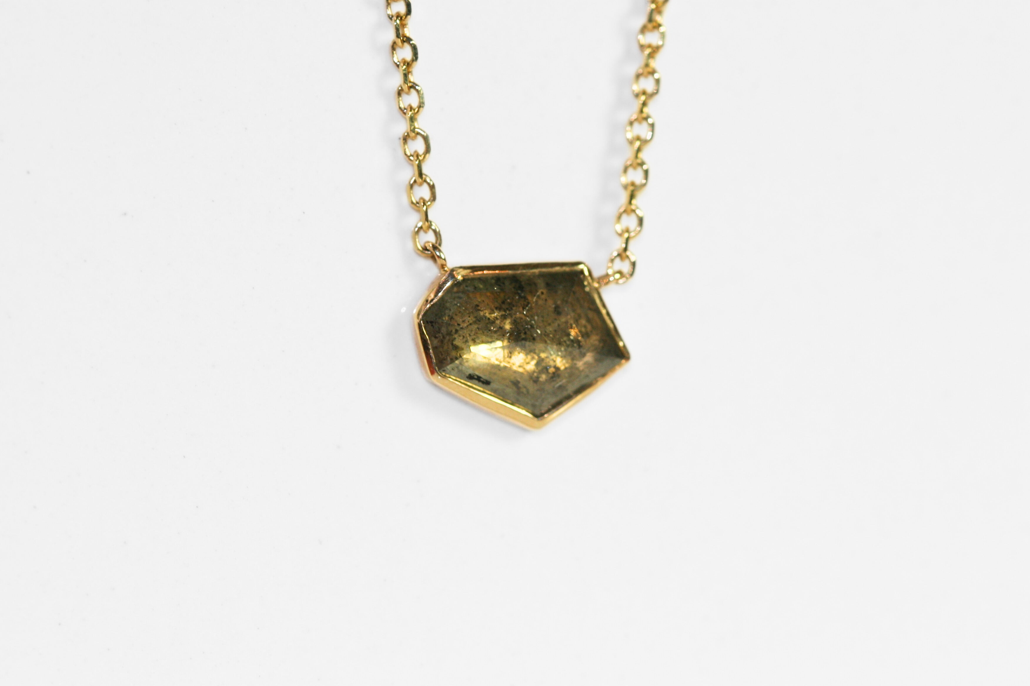 Abstract salt and pepper diamond is bezel set in yellow gold. Pendant, attached to a yellow gold rolo chain. Diamond has interesting inclusions.