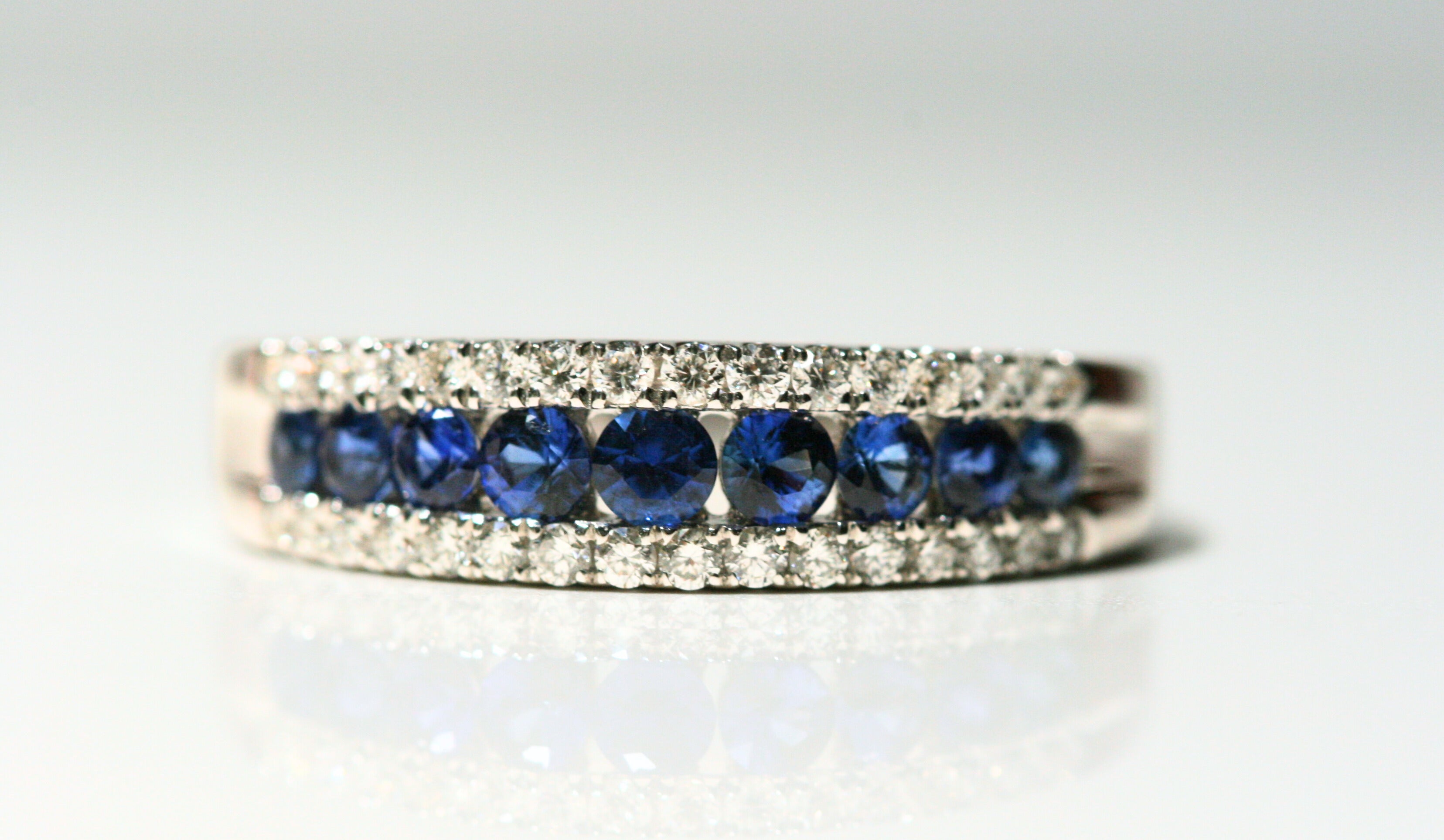 A close up of the front of the ring. Each sapphire is round and deep blue, and they are set between bands of diamonds on the top and bottom. Local SF jewelry, San francisco, Luxury, hand made, Bay area, gift for her, gift for him.