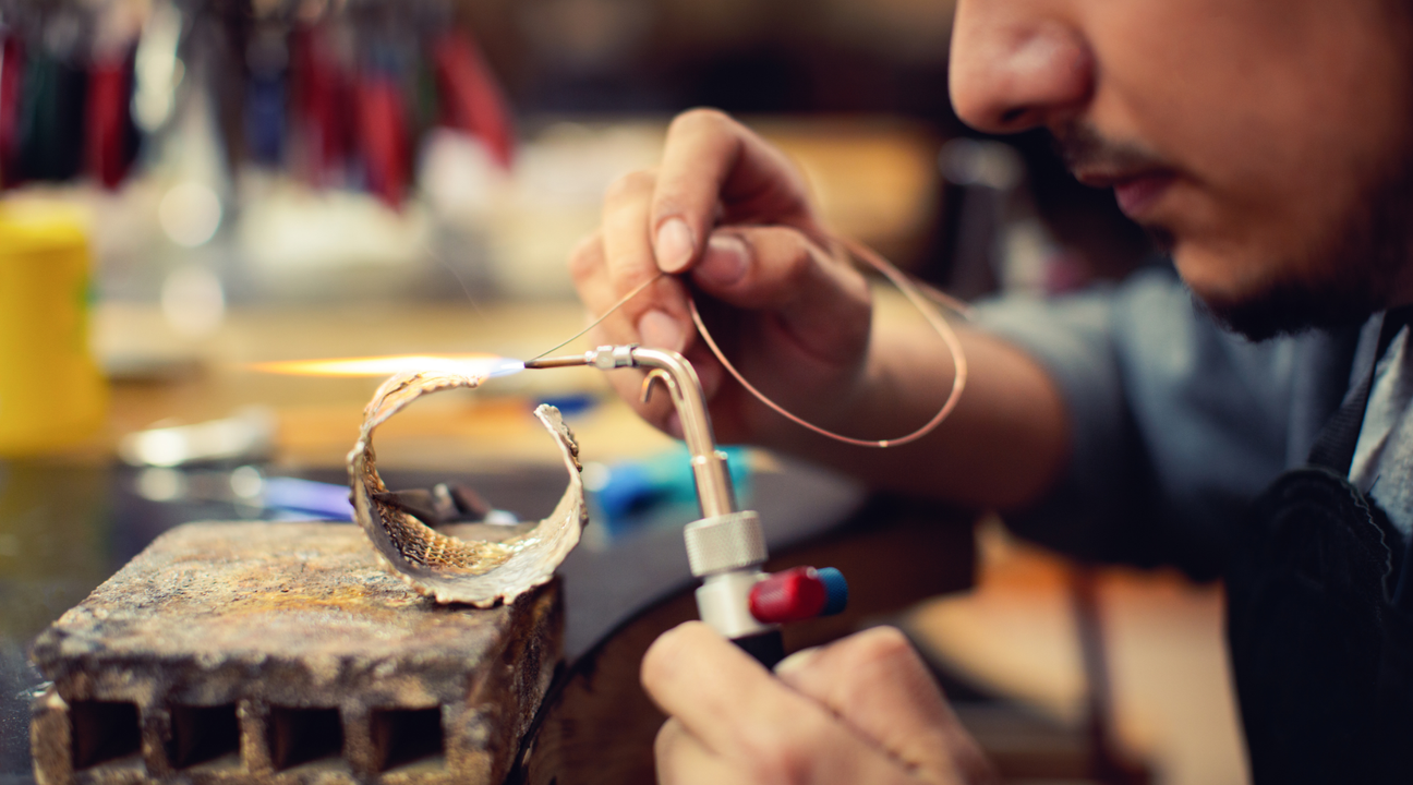 Jeweler inspecting a gold ring under a magnifying glass for common jewelry repairs.