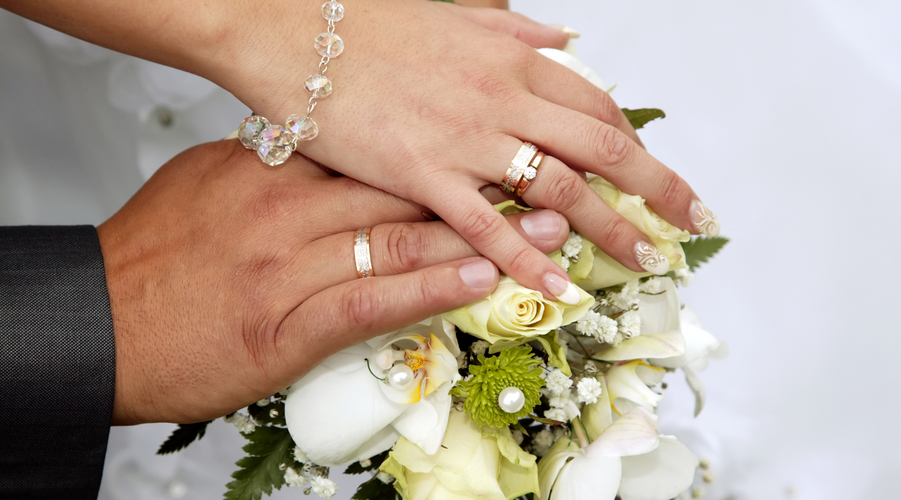 Bride and groom holding ahnds with wedding rings