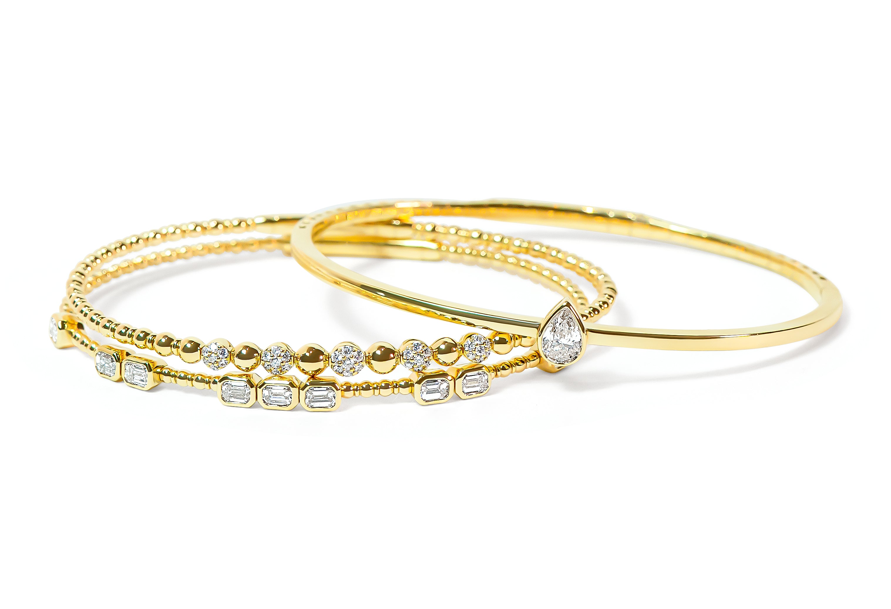 Set of gold bangles with diamond accents on a white background