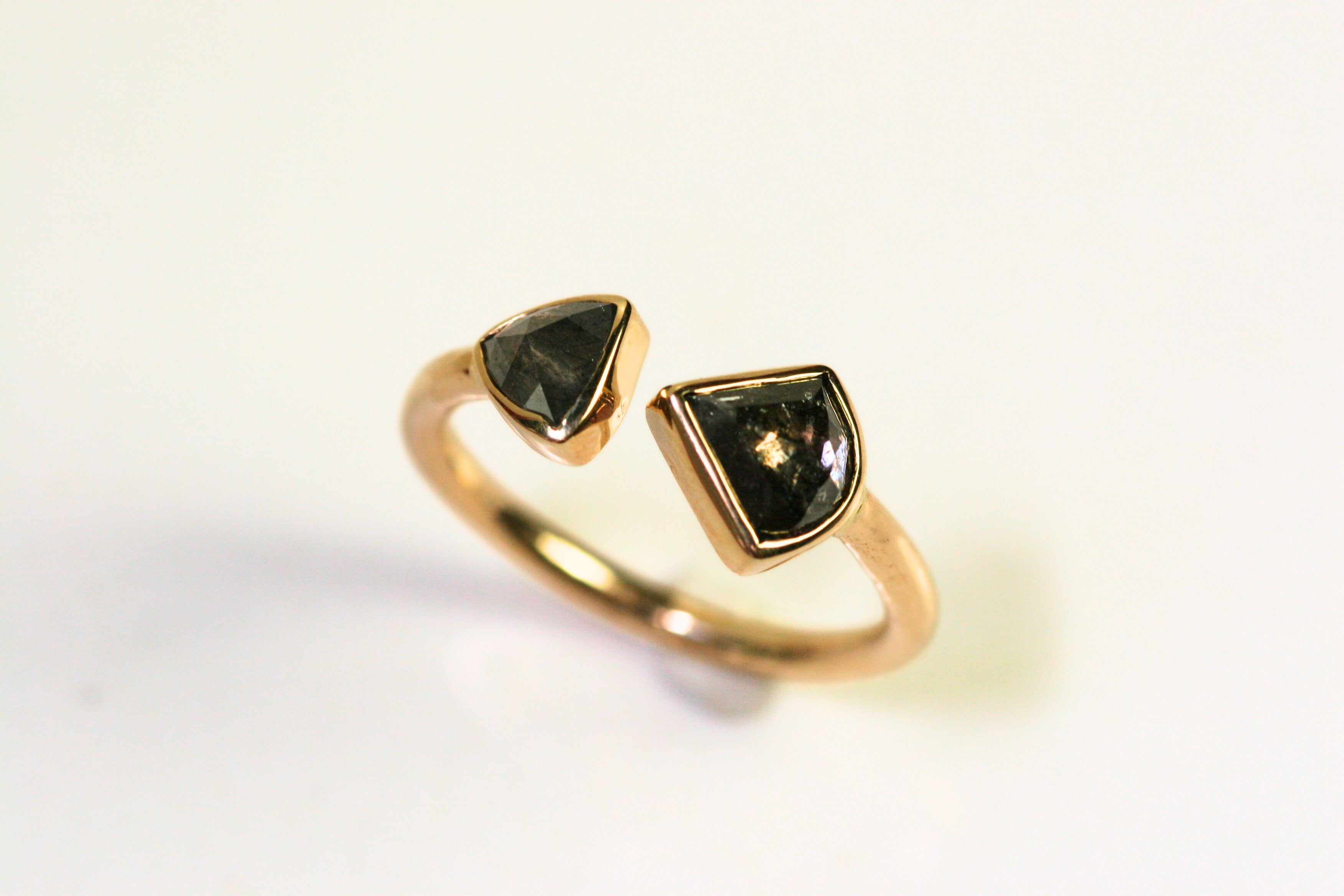 Unique ring. Two triangular diamonds are bezel set and the band is fully rounded. They meet in the middle with a slight space between the two.