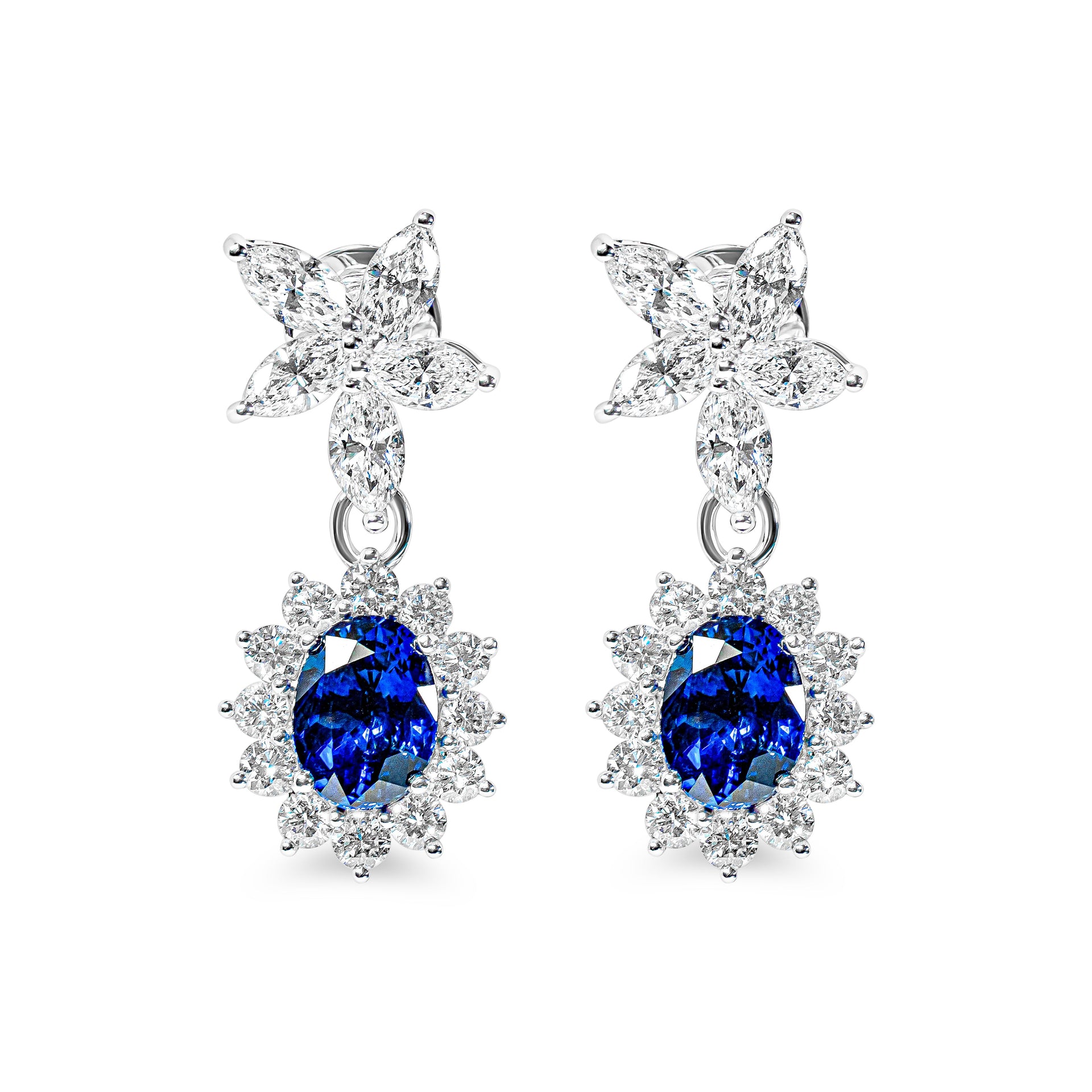 Pair of earrings with blue sapphires and flower-shaped tops on a white background
