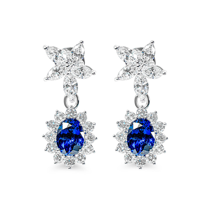 Pair of earrings with blue sapphires and flower-shaped tops on a white background
