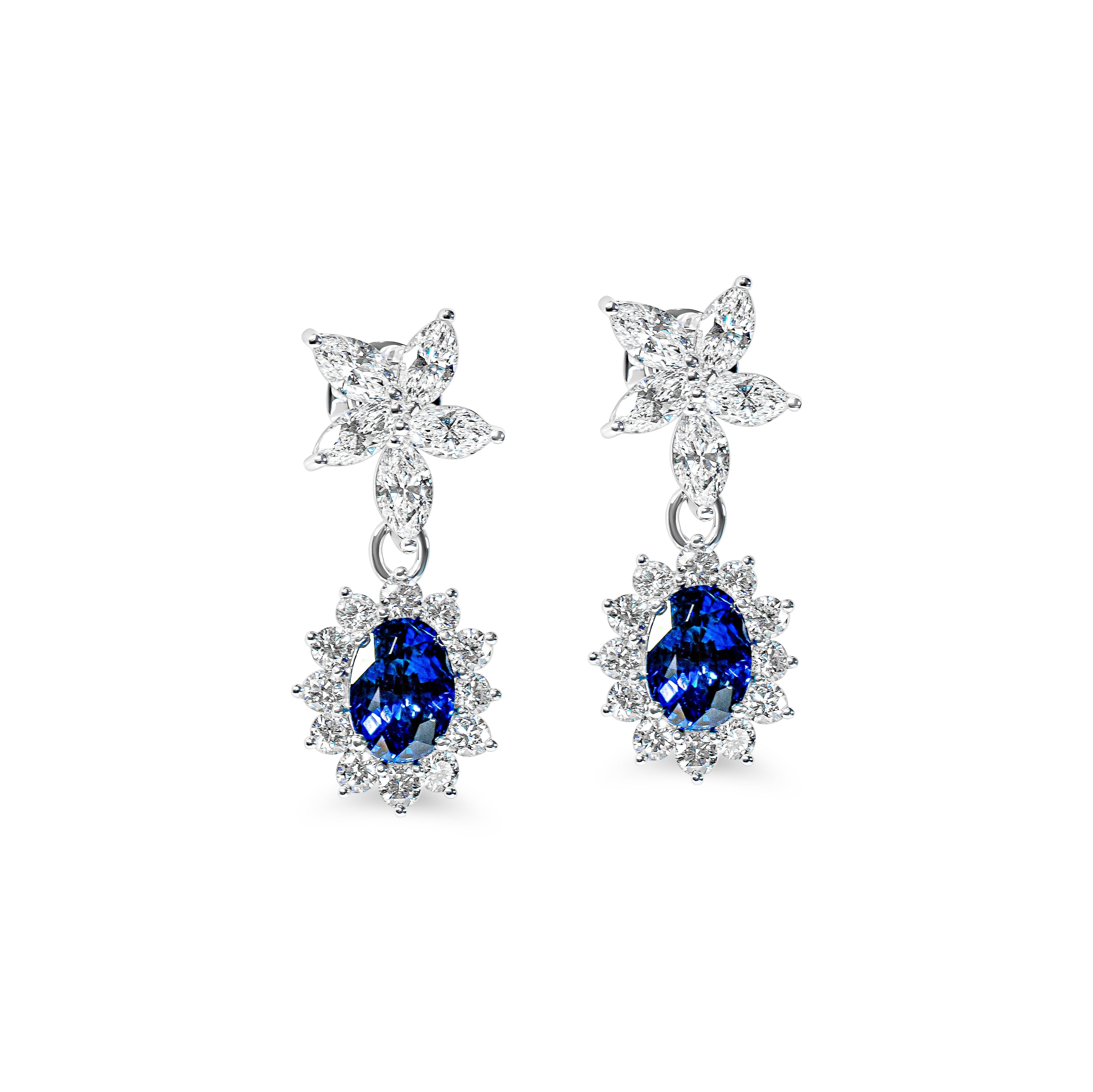 Pair of earrings with blue sapphires and flower-shaped designs on a white background