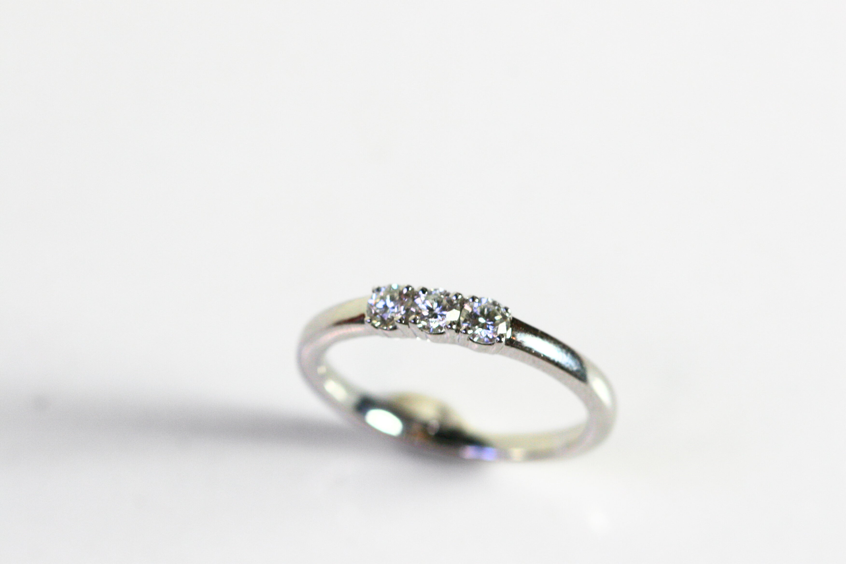 White gold ring with 3 round diamonds in the center. The band is the same thickness as the stones. This photo is a head on view of the ring.