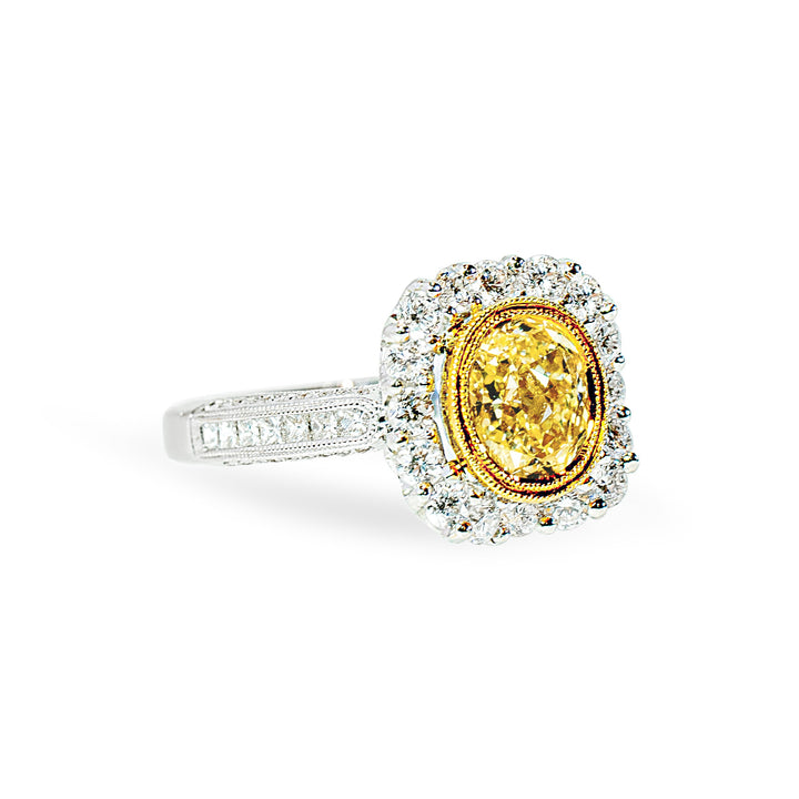 Ring with a yellow diamond and diamond halo on a white background