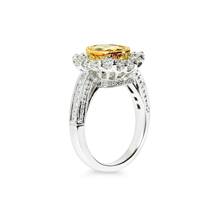 Ring with a yellow diamond and diamond halo on a white background