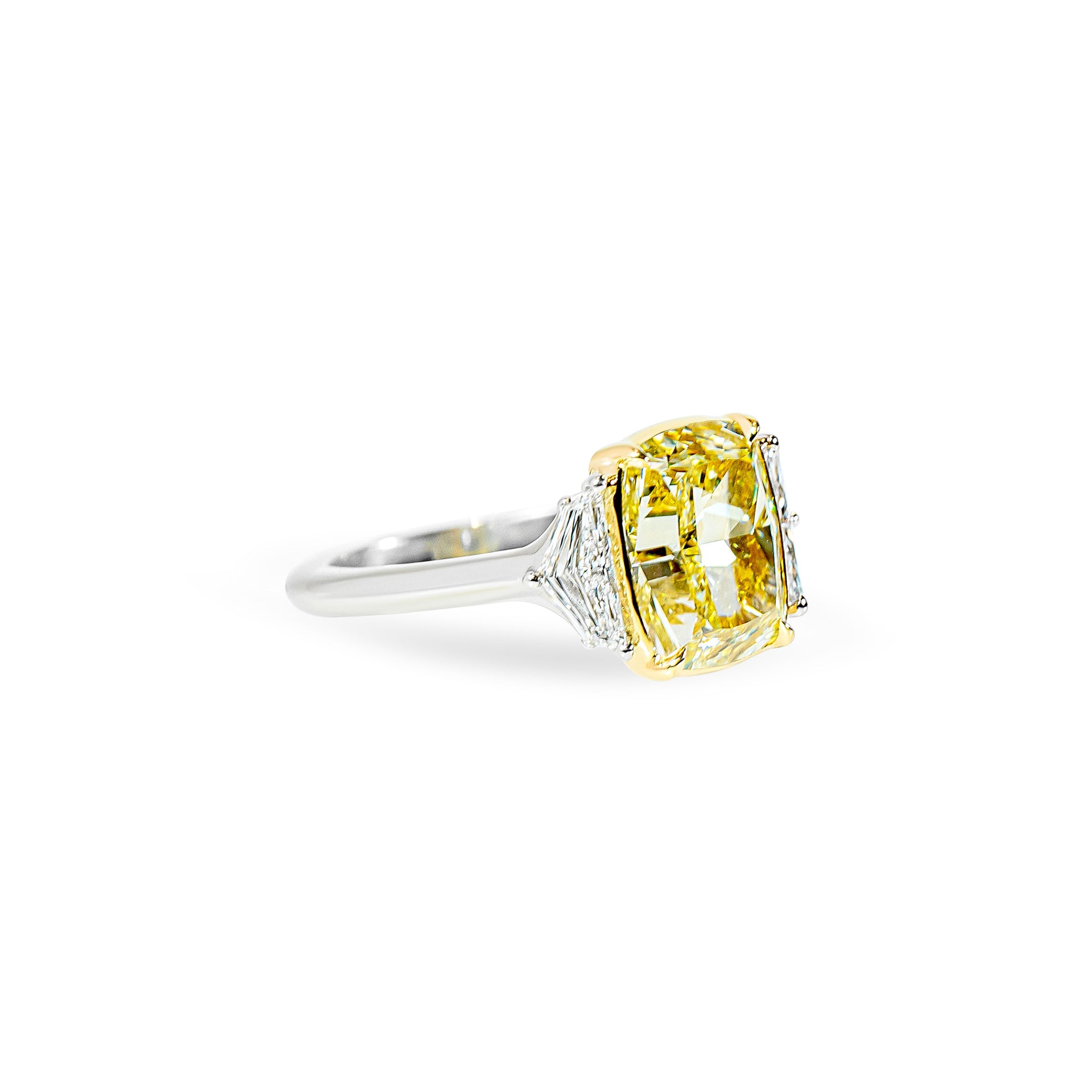 Ring with a yellow diamond and two smaller clear cadillac diamonds on a white background