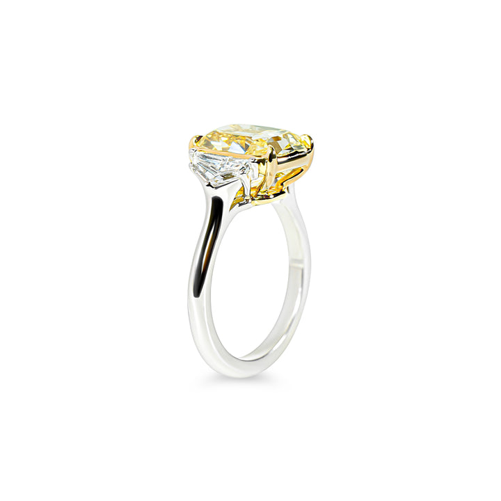 Ring with a yellow diamond and two smaller clear cadillac diamonds on a white background