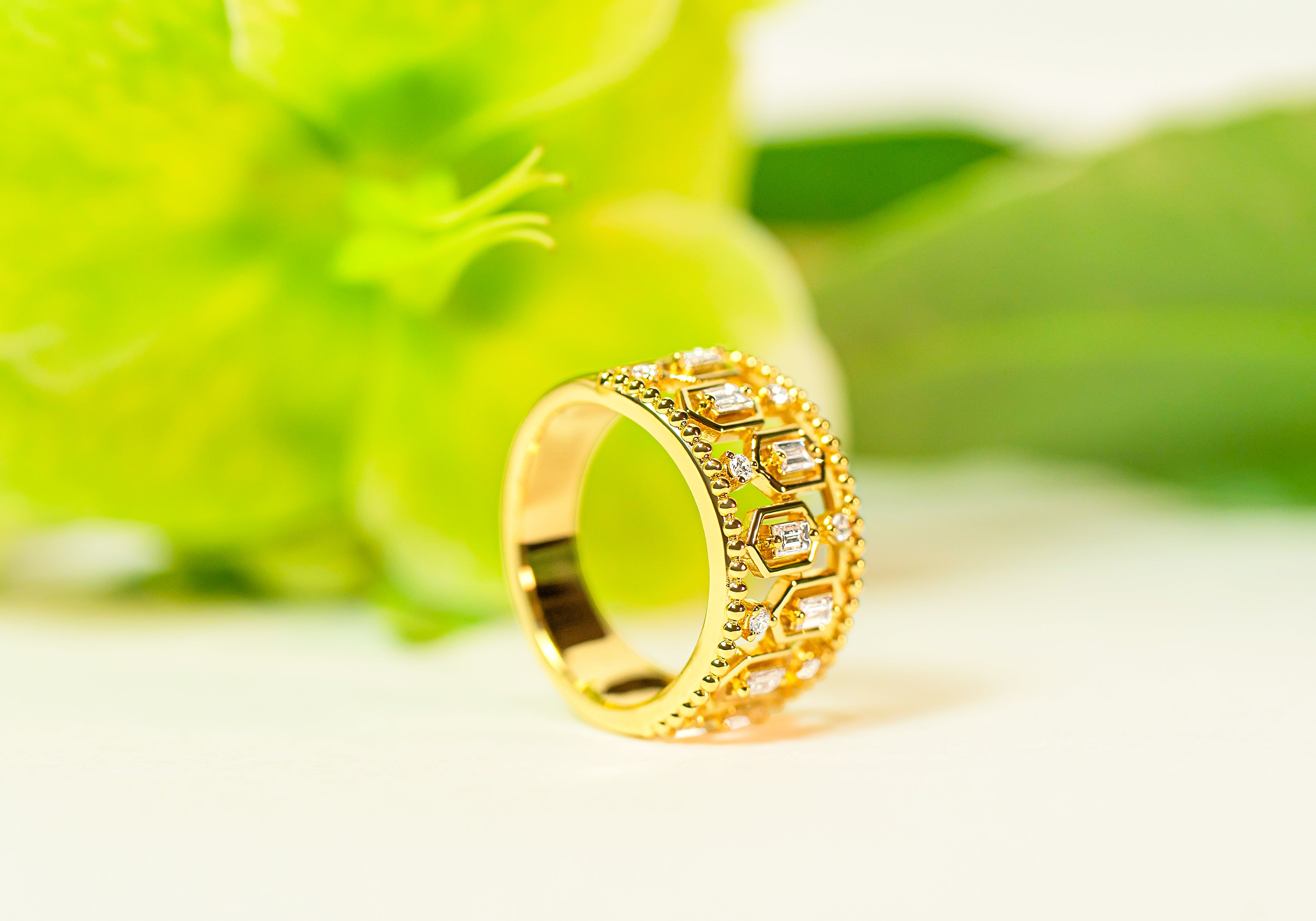 Gold ring with diamond accents on a blurred green background