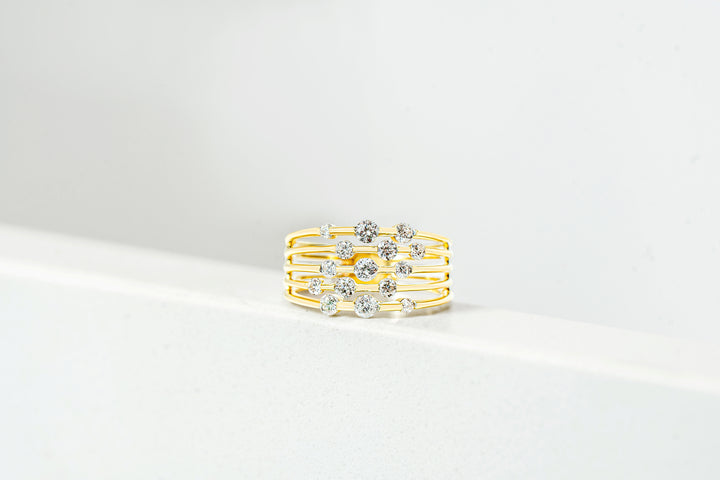 A multi-band gold ring adorned with five rows of round diamonds, displayed on a clean white surface against a white background.