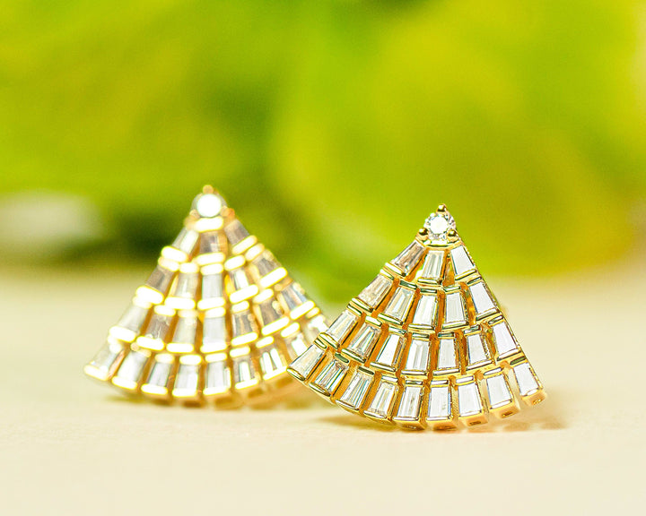 Gold fan-shaped earrings with diamonds on a light background