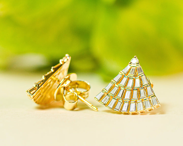 Gold fan-shaped earrings with diamonds on a light background