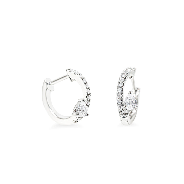 A pair of silver huggie hoop earrings with pear-cut clear diamonds and pave round diamonds, shown on a clean white background.