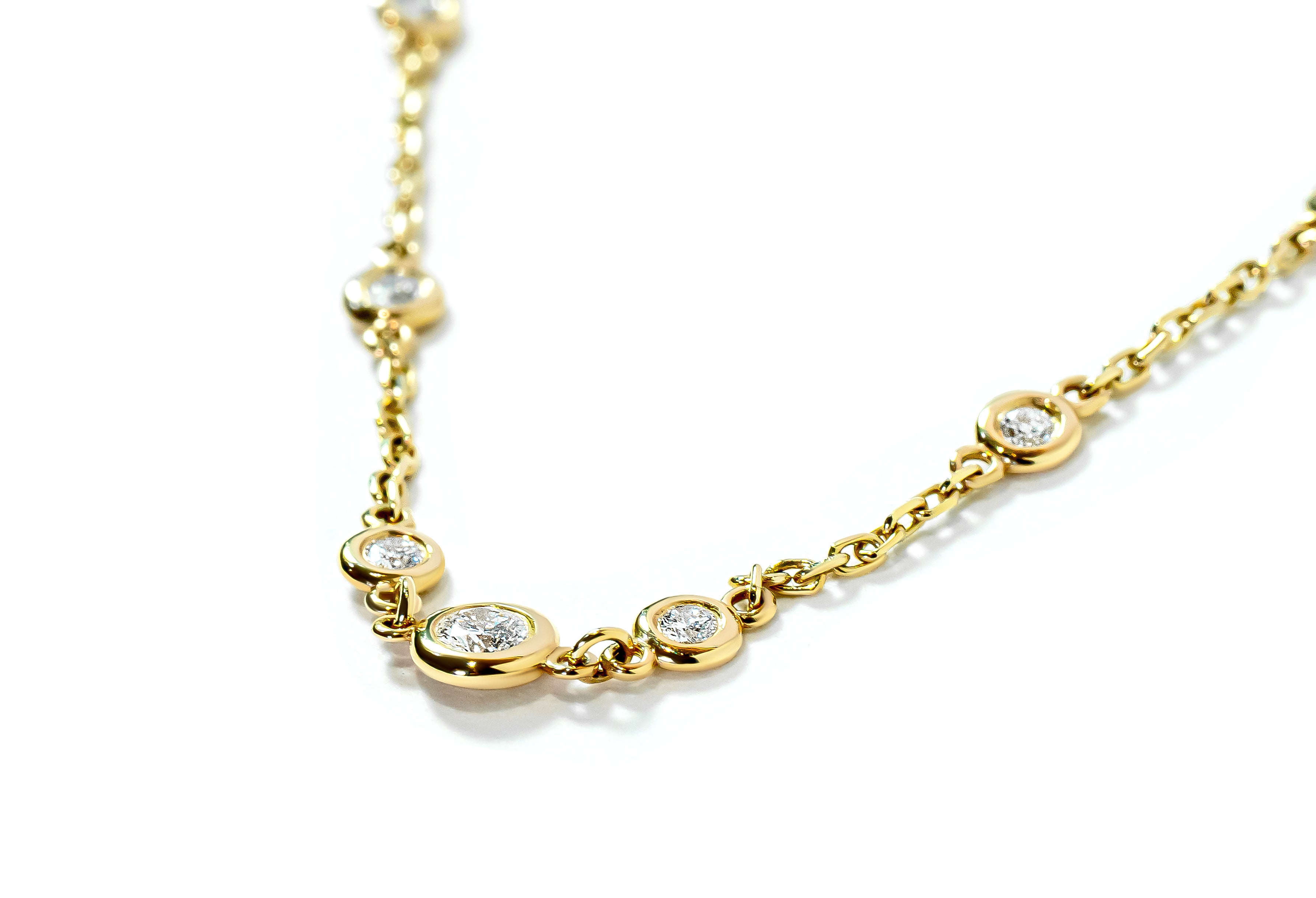 Gold necklace with small bezel-set diamonds on a white background