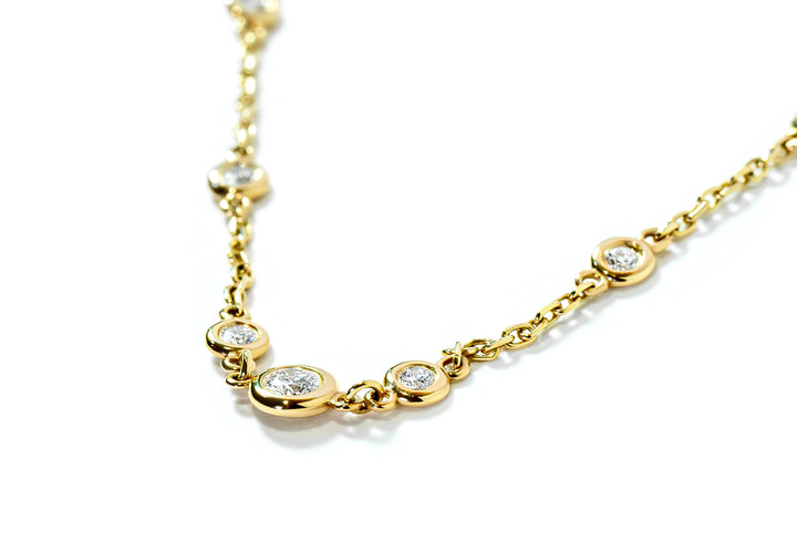 Gold necklace with small bezel-set diamonds on a white background