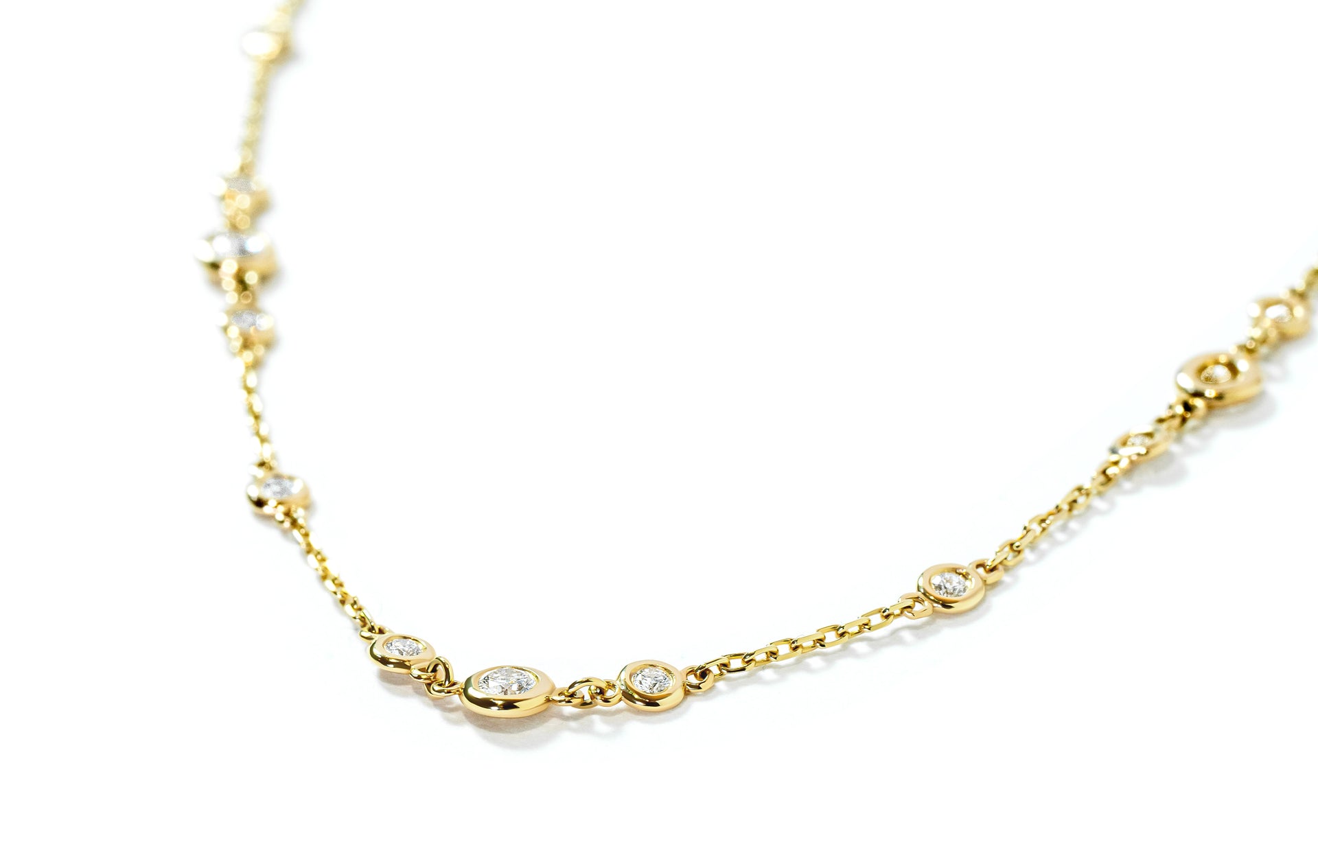 Gold necklace with small bezel-set diamonds on a white background