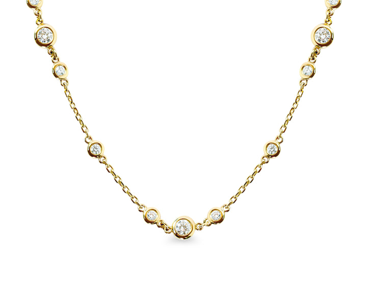 Gold necklace with small bezel-set diamonds on a white background