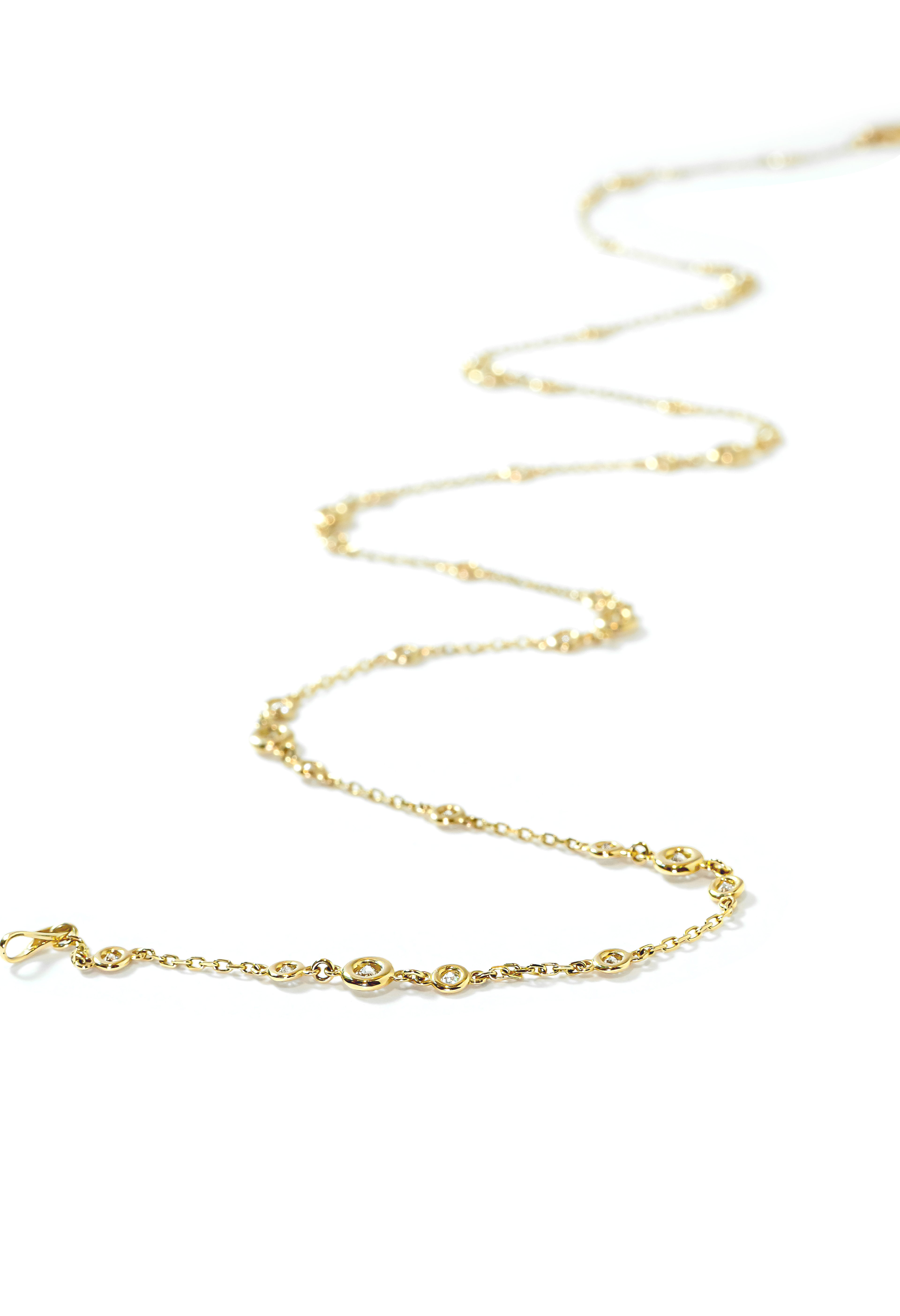 Gold necklace with small bezel-set diamonds on a white background