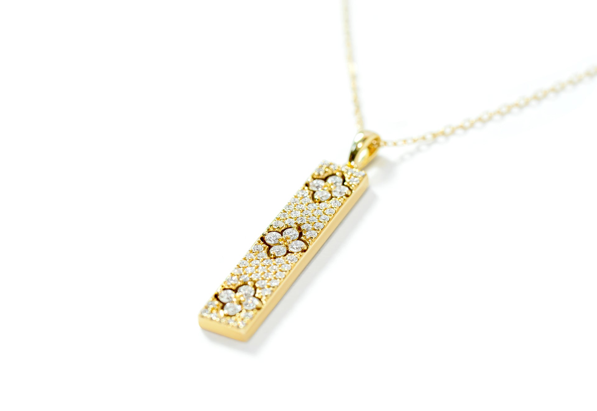 Gold bar necklace with a diamond pave pendant on a white background 