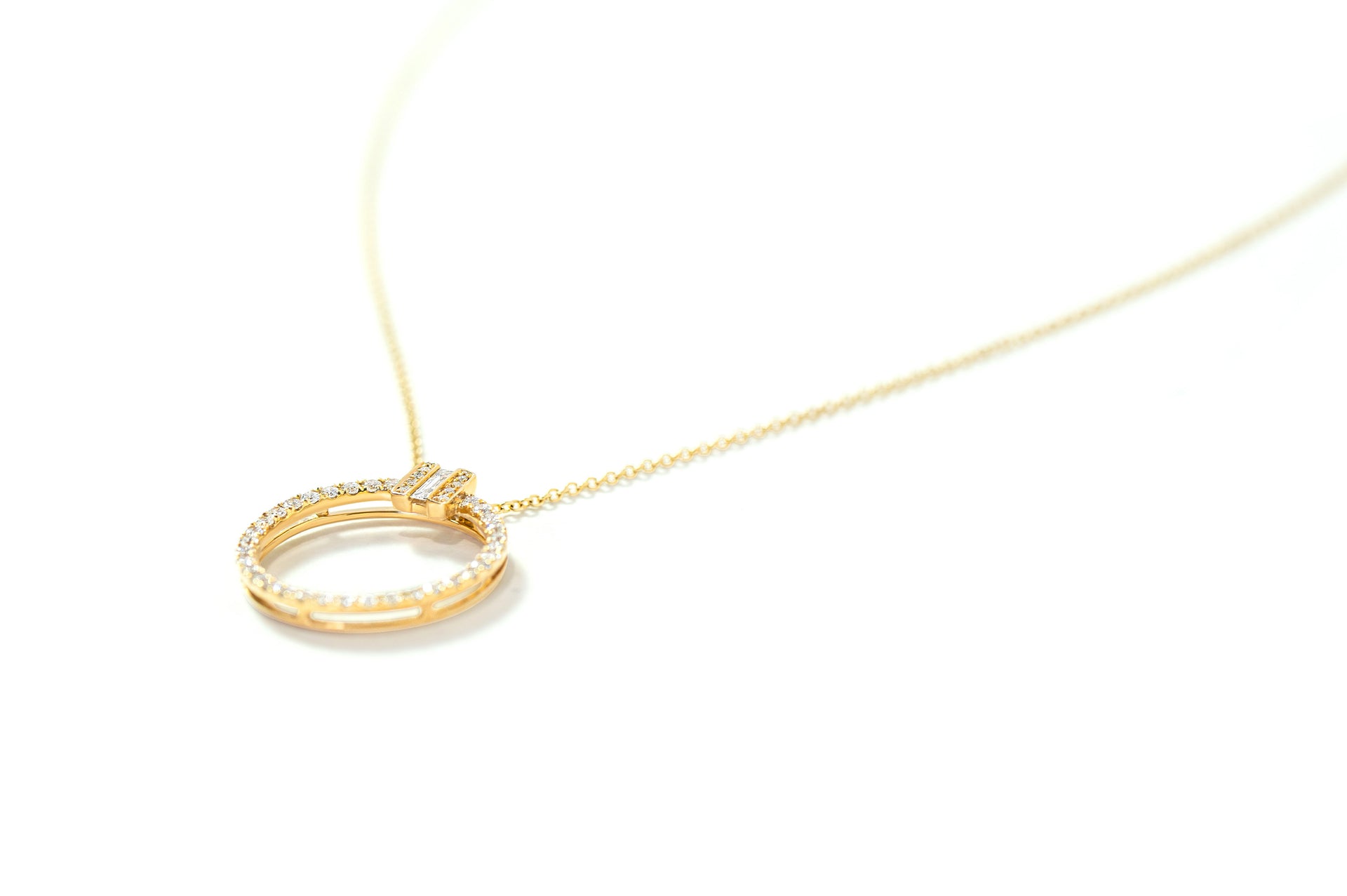 Gold necklace with a circular diamond pendant on a white background