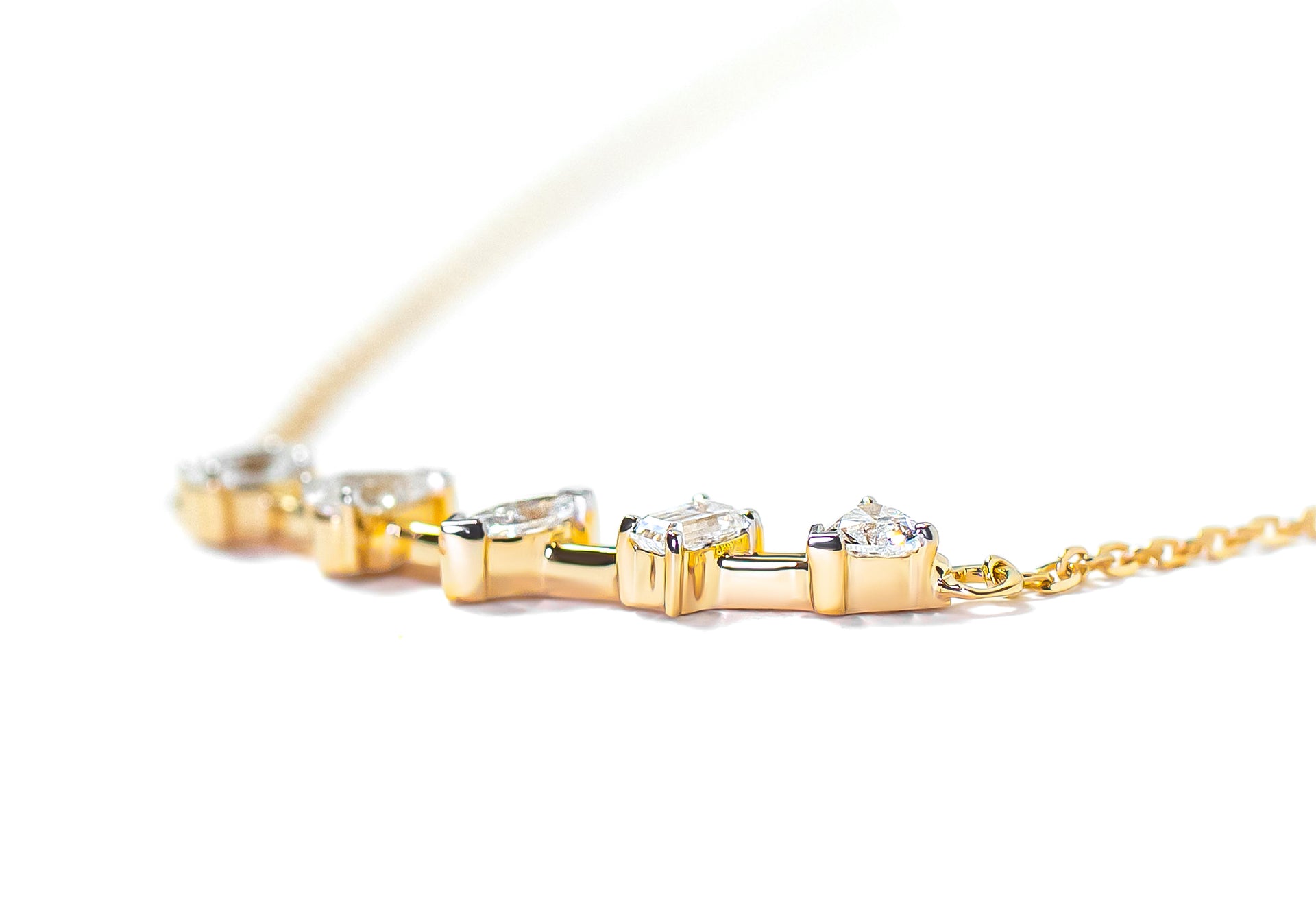 Gold bar necklace with mix-shaped diamonds on a white background