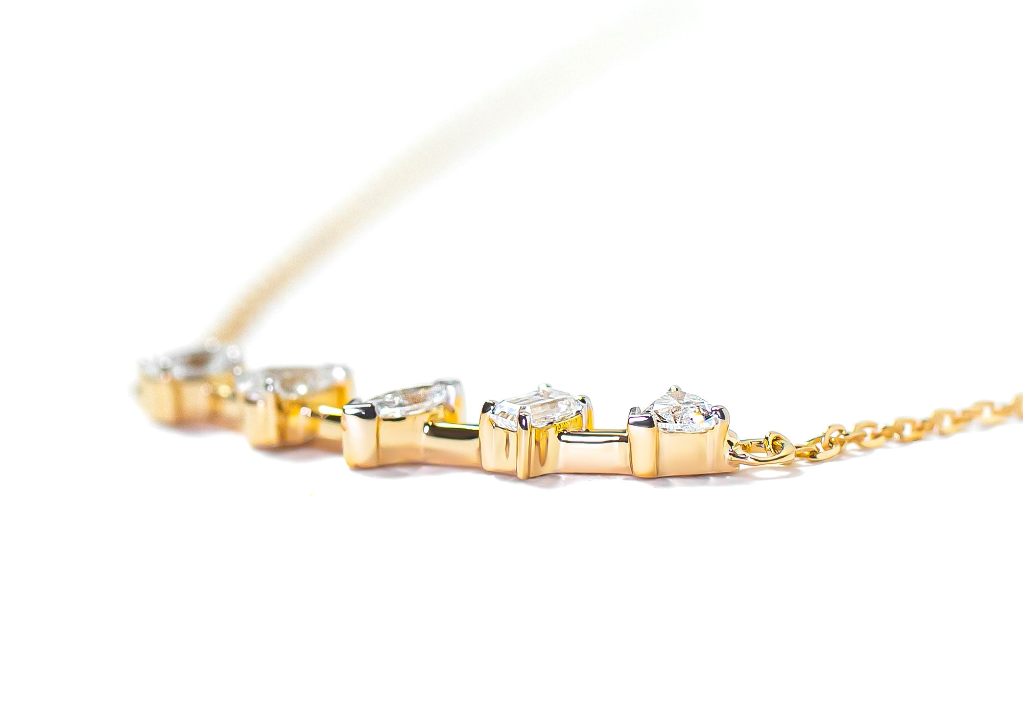 Gold bar necklace with mix-shaped diamonds on a white background