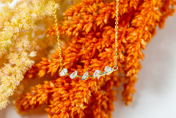 Gold bar necklace with mix-shaped diamonds on a floral background
