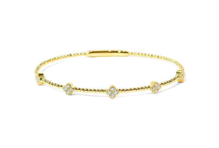 Gold bracelet with diamond clover charms on a white background