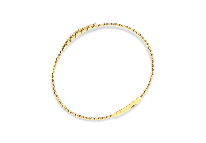 Top view of gold bangle with small diamonds on a white background