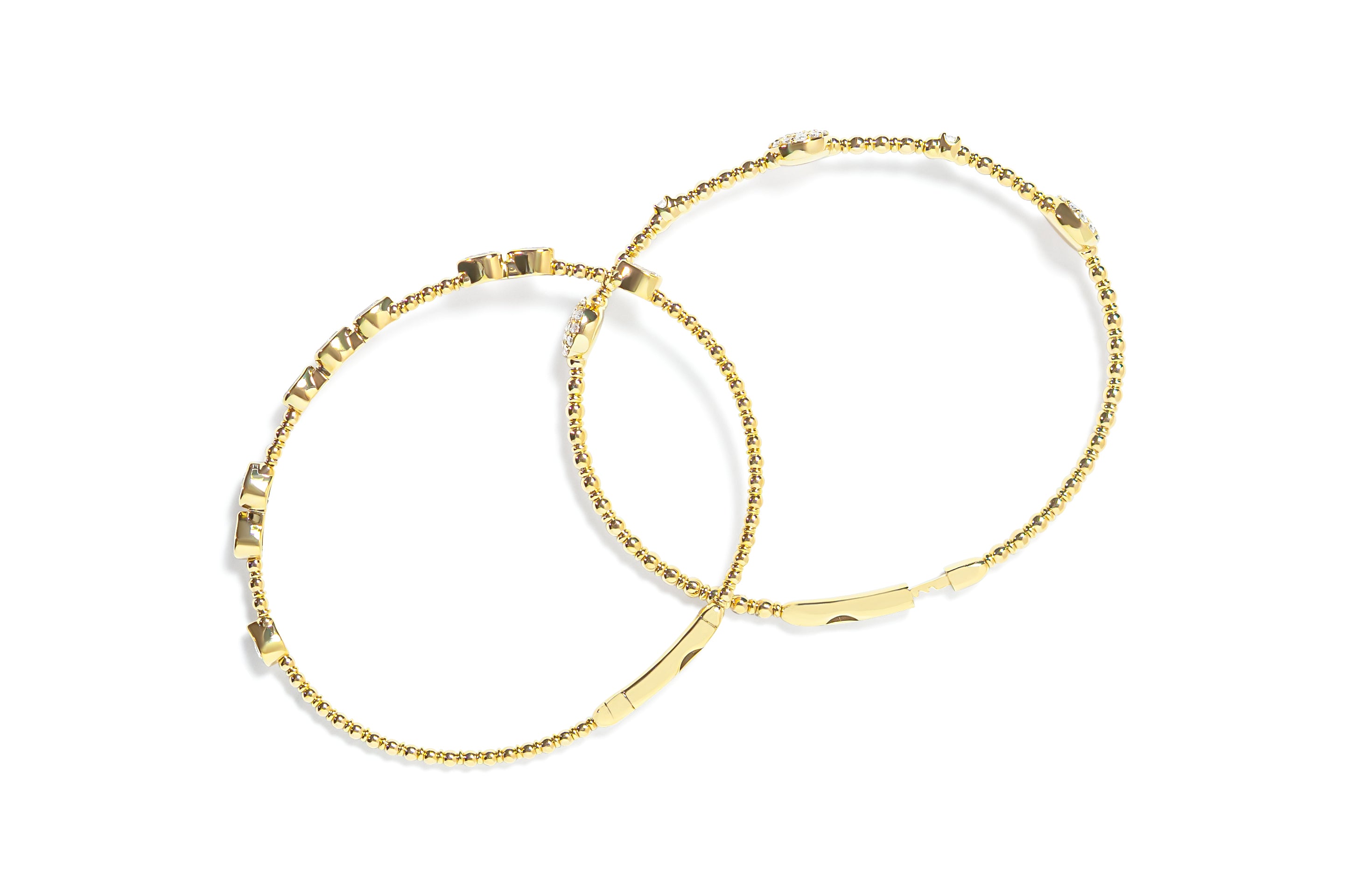 Top view of two gold bangles with diamond accents on a white background