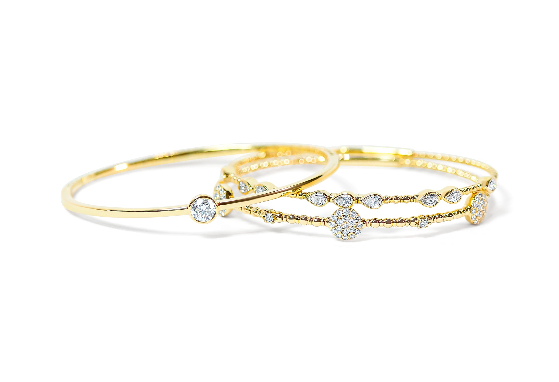 Set of gold bangles with diamond accents on a white background