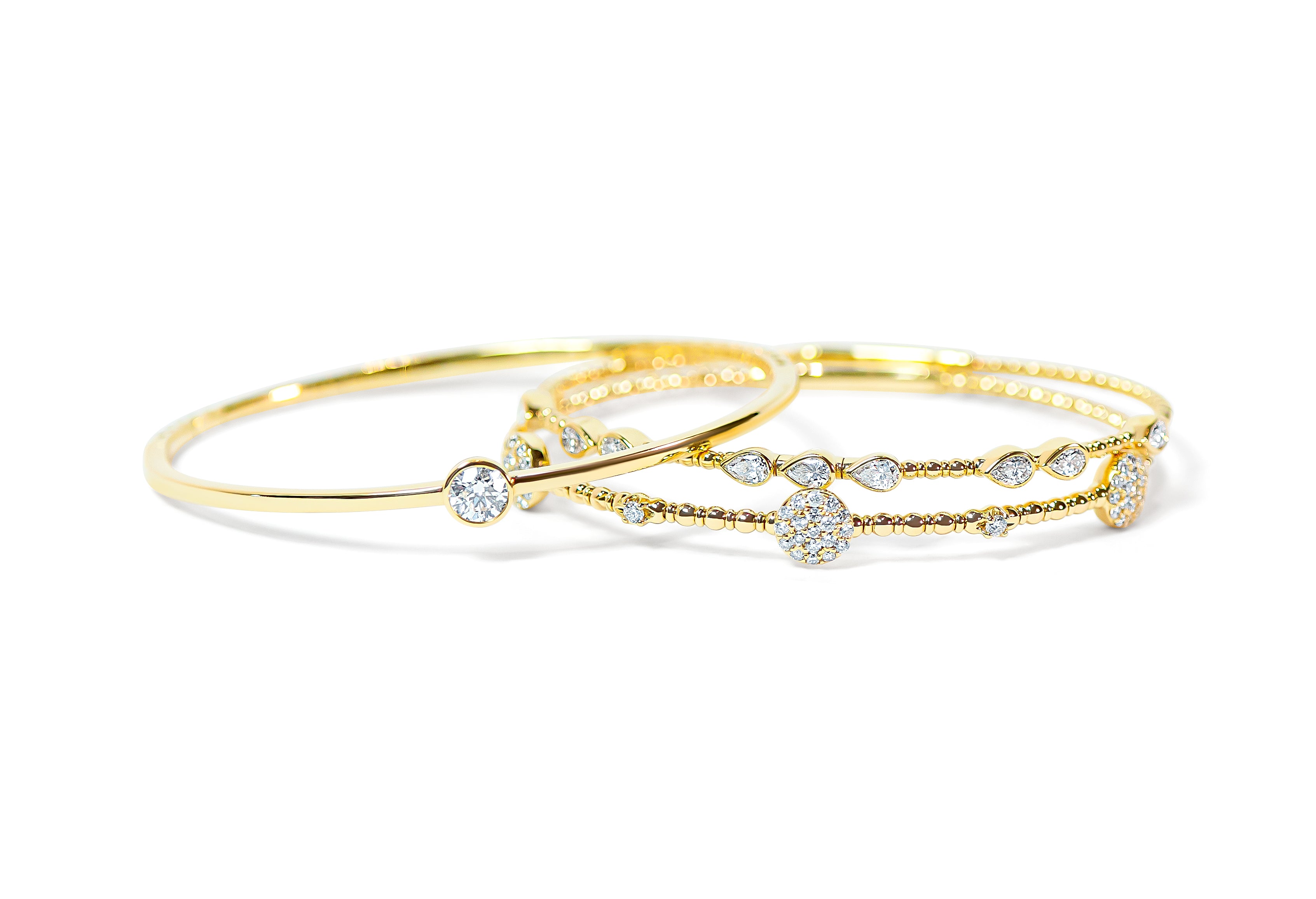 Set of gold bangles with diamond accents on a white background
