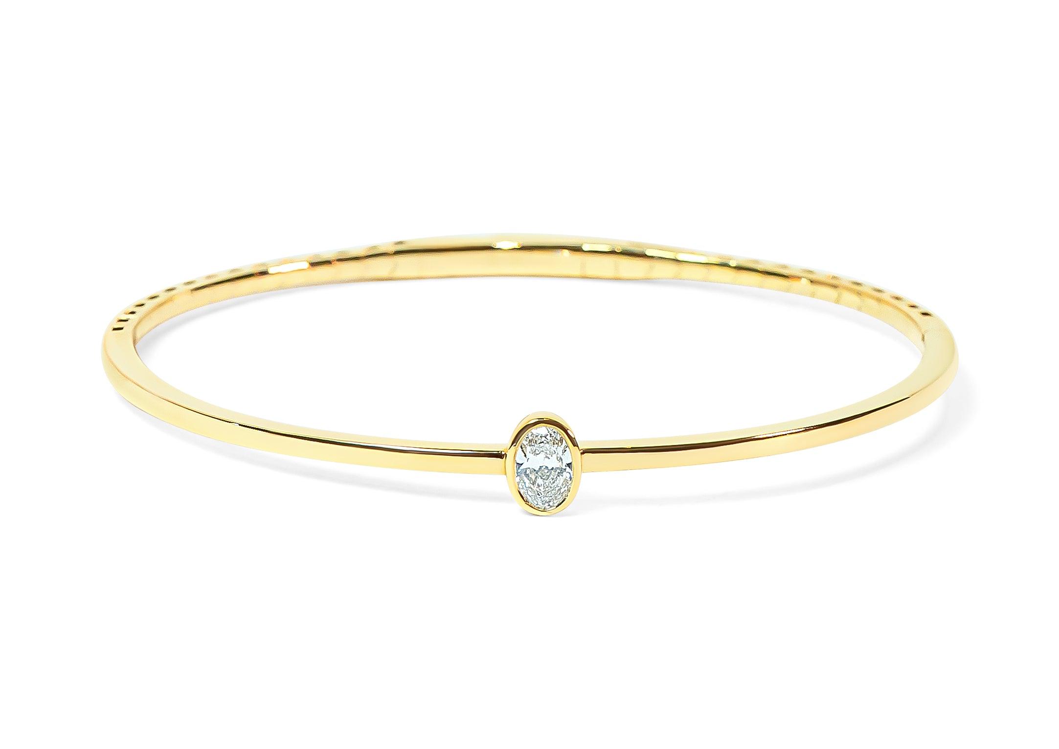 Gold bangle with an oval-shaped diamond on a white background