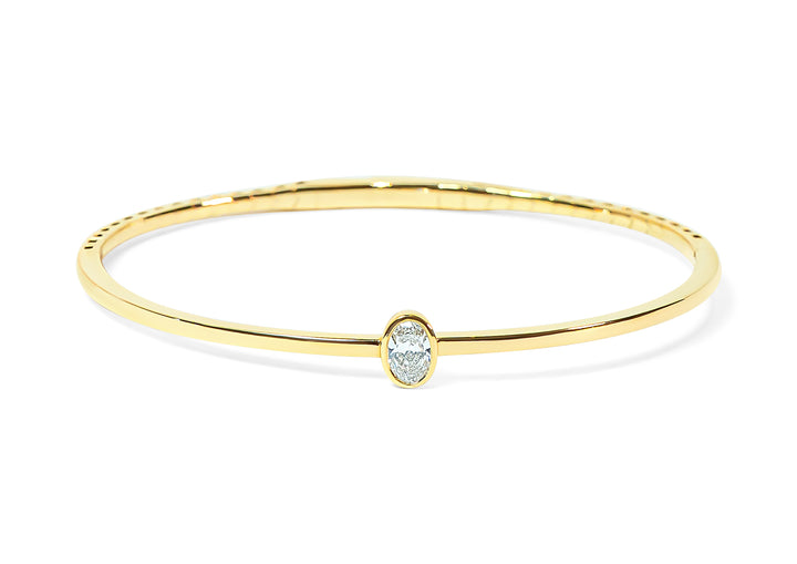 Gold bangle with an oval-shaped diamond on a white background