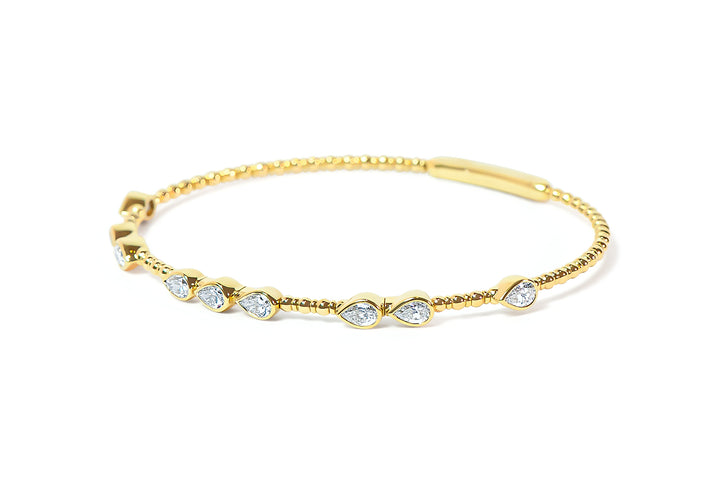 Gold bangle with teardrop or pear-shaped diamonds on a white background