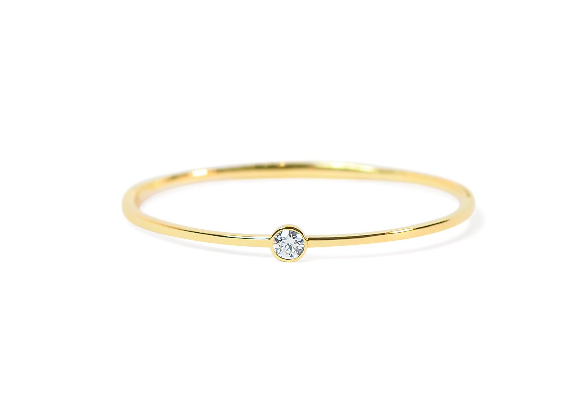 Gold bangle with a small round diamond on a white background