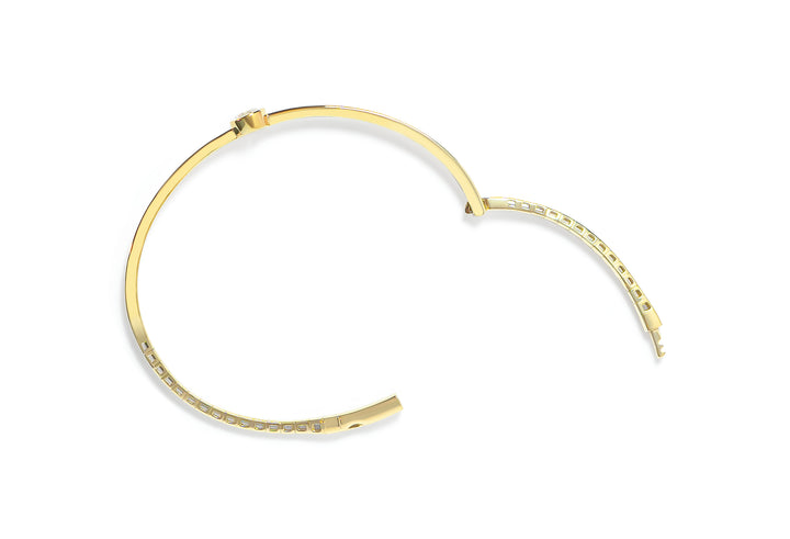 Top view of an open gold bangle with a round diamond on a white background