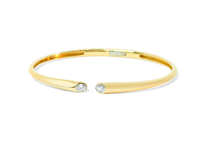 Gold bangle with two oval diamonds on a white background