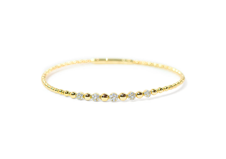 Gold bangle with pave diamonds and beaded-texture on a white background